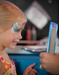 Girl looking at her painted face in the mirror