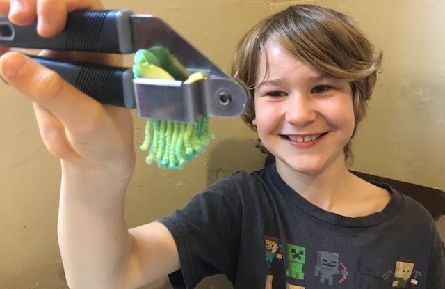 Boy making playdough hair with a garlic press